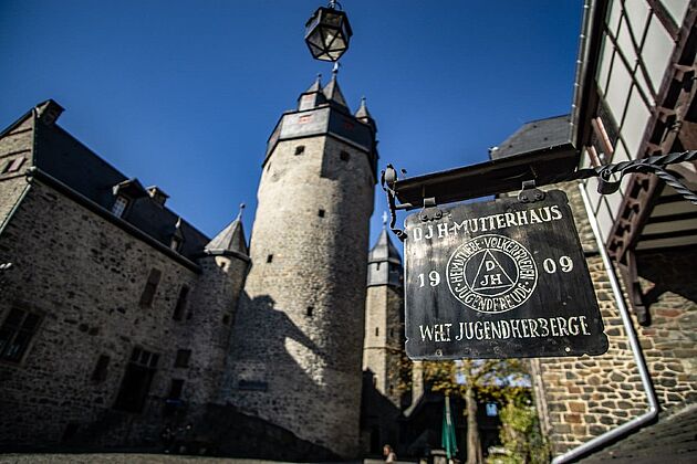 Die Burg Altena neben einem Schild der ersten Jugendherberge
