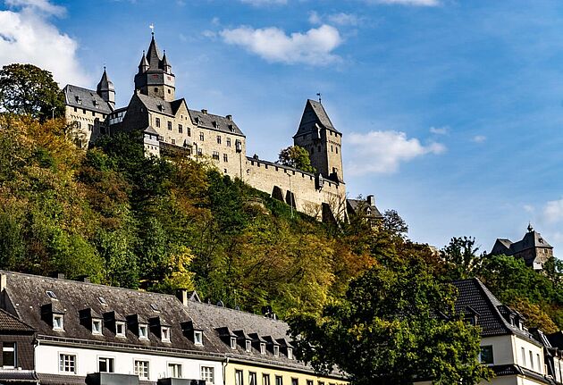Burg Altena vor grünen Bäumen, im Vordergrund Häuser